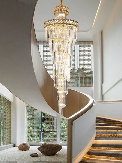 A modern gold stainless steel crystal chandelier with gold accents hangs above a spiral staircase decorbites gold stainless
