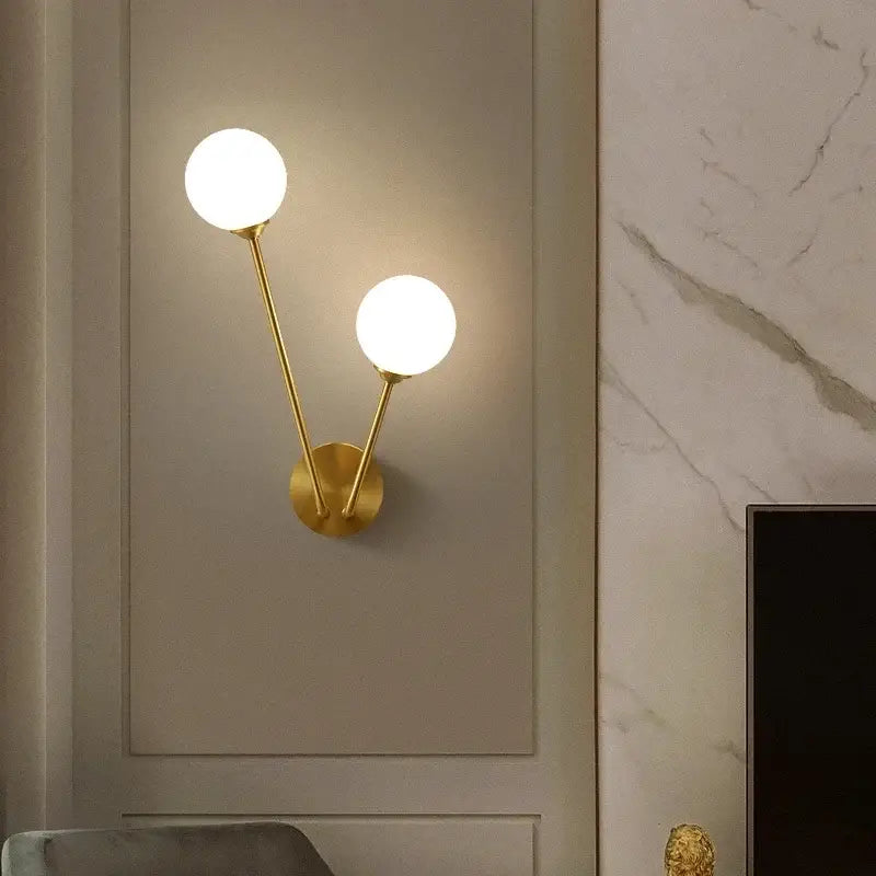 Modern gold starburst ball glass ceiling light with gold-toned wall sconce and two frosted glass shades for living room