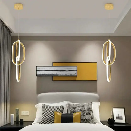 Modern gold steel pendant light with interlocking rings and integrated led lighting hangs symmetrically above bed decorbites gold steel pendant