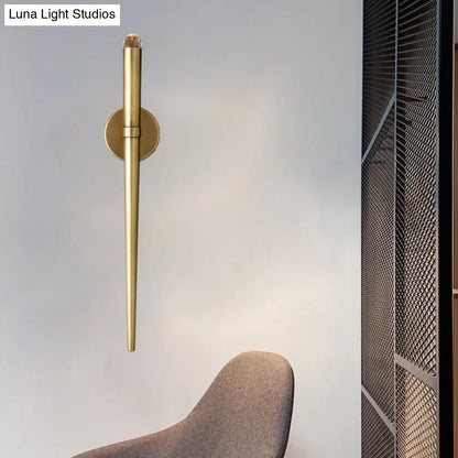 A sleek gold finished modern wall lamp with a tapered crystal led design for living room lighting