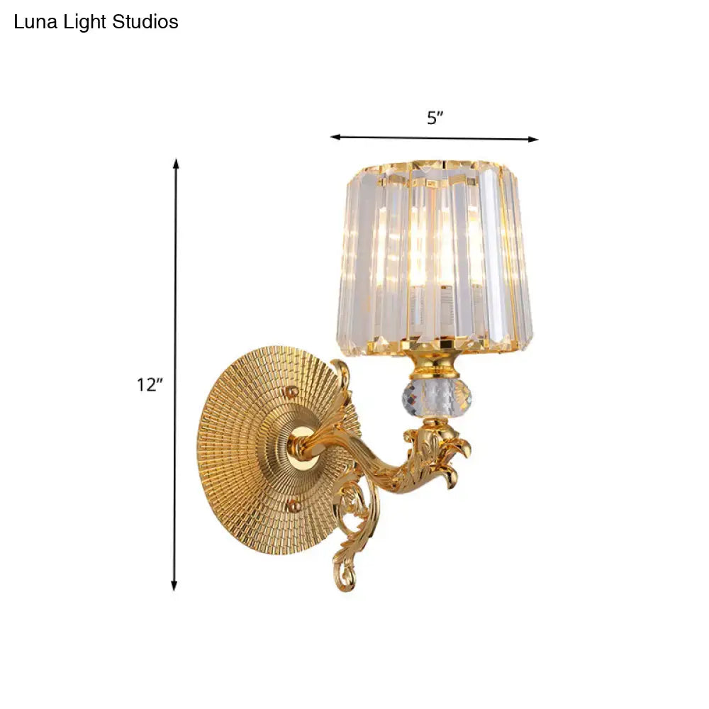 Modern gold tapered wall light fixture with ornate scrollwork arm and crystal-fringed lampshade for bedroom use