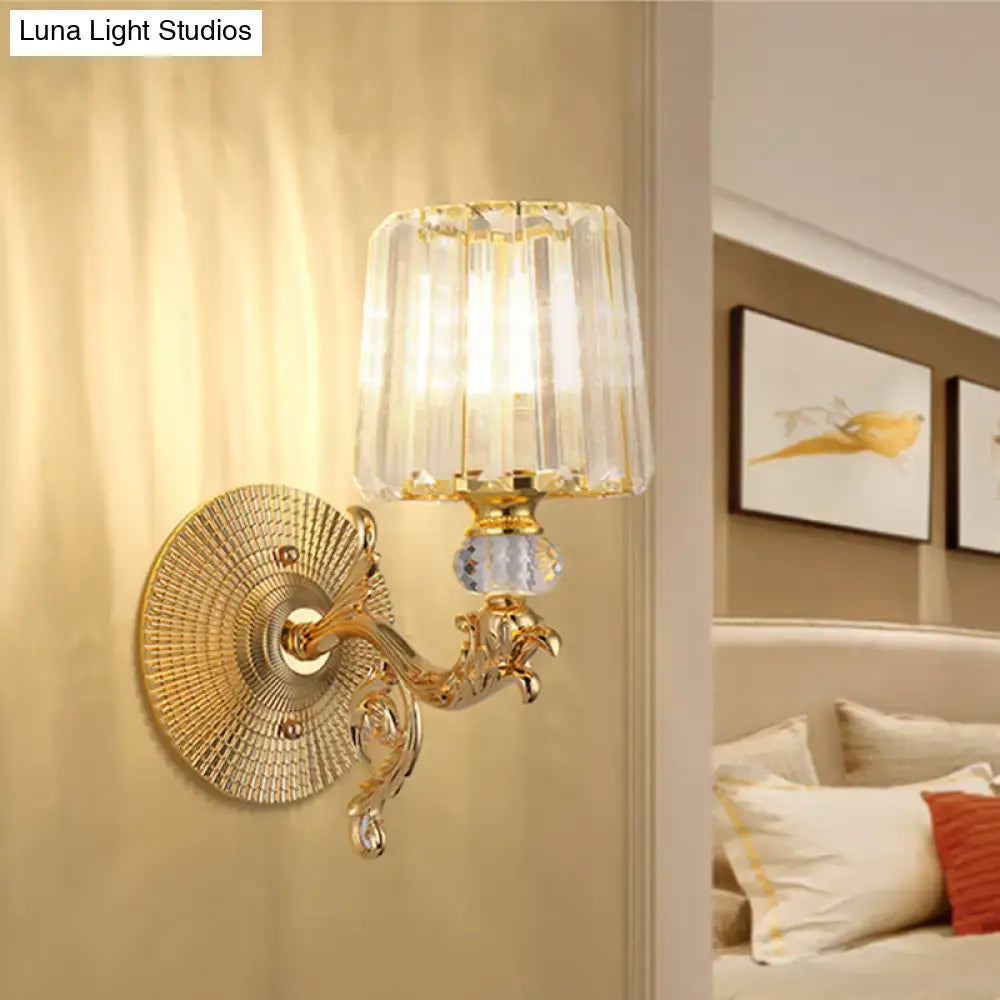 Gold tapered wall light fixture featuring a gold-toned ornate design with a faceted crystal shade and decorative scrollwork