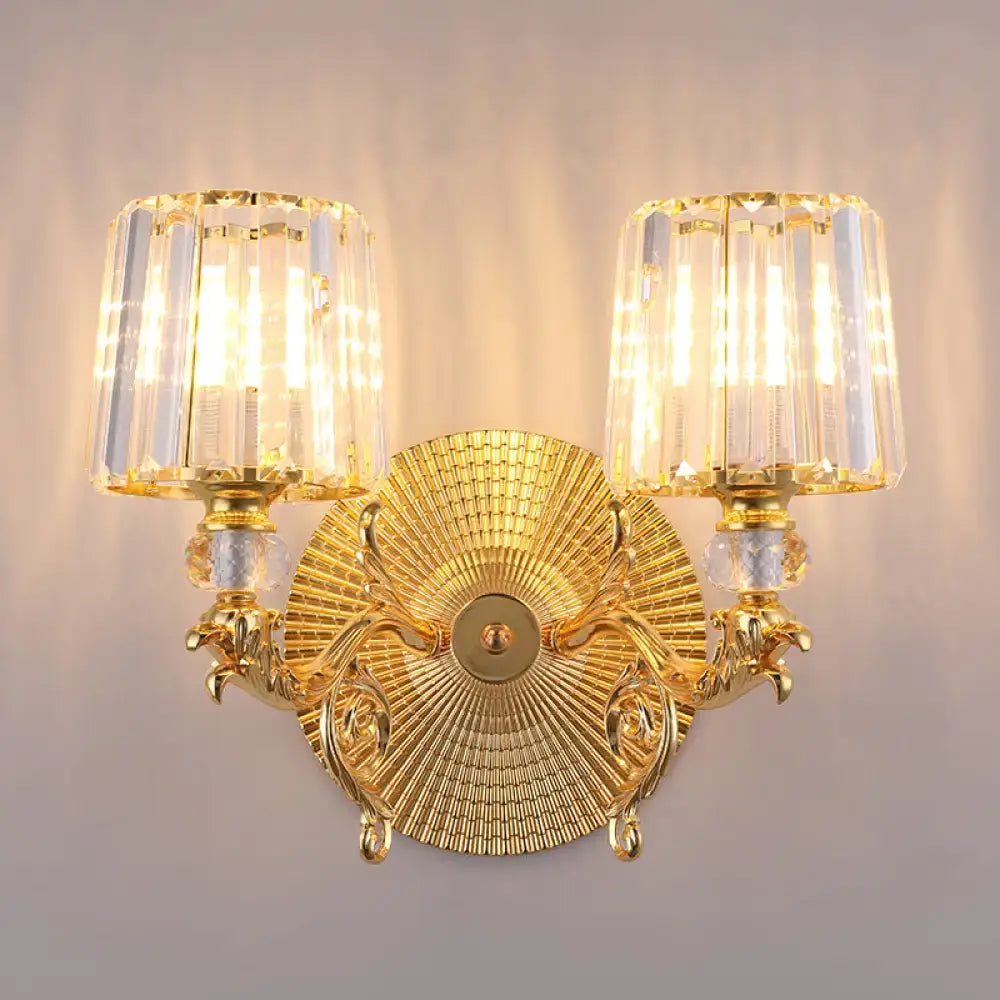 Modern gold tapered wall light fixture featuring ornate gold finish with two crystal-encased light fixtures and sunburst design