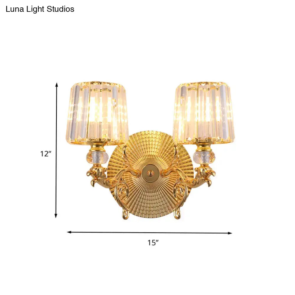 Gold tapered wall light fixture with two fluted crystal shades and ornate sculpted arms for bedroom decor