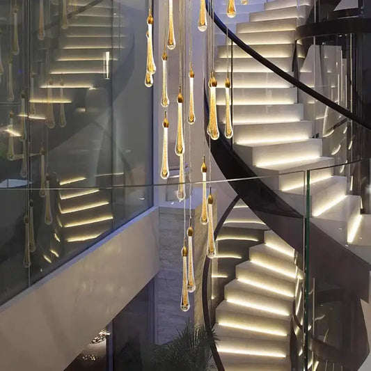 Modern gold teardrop crystal pendant lights hang elegantly from the ceiling ideal for staircase pendant light use