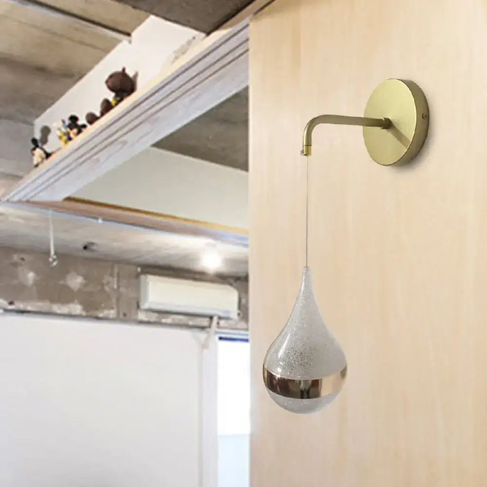 A sleek modern gold teardrop wall sconce with brass finish direct wired electric light for bedroom use