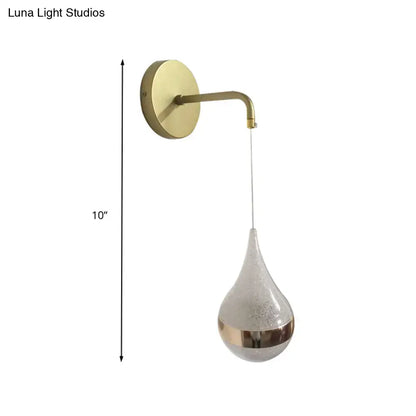 A sleek brass-finished modern gold teardrop wall sconce with frosted glass shade direct wired electric light for bedroom