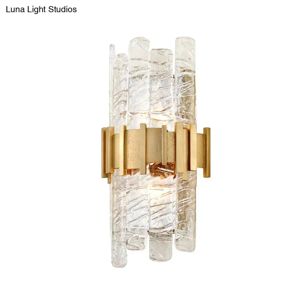 Modern gold sconce light fixture featuring clear textured glass rods with a gold-toned metal frame for bedroom use