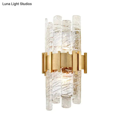 Modern gold sconce light fixture featuring clear textured glass rods with a gold-toned metal frame for bedroom use