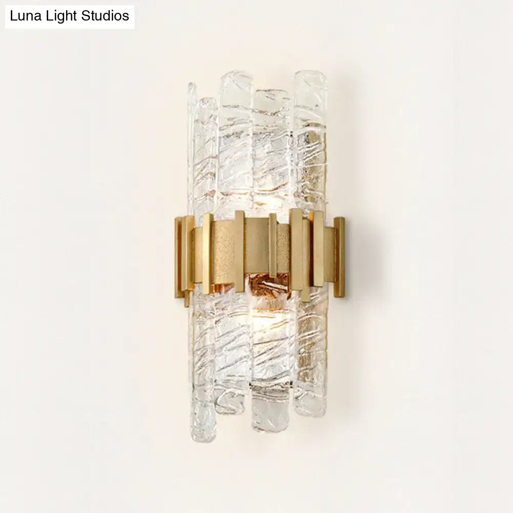Modern gold sconce light fixture featuring textured glass and metal with a sculptural design for bedroom walls