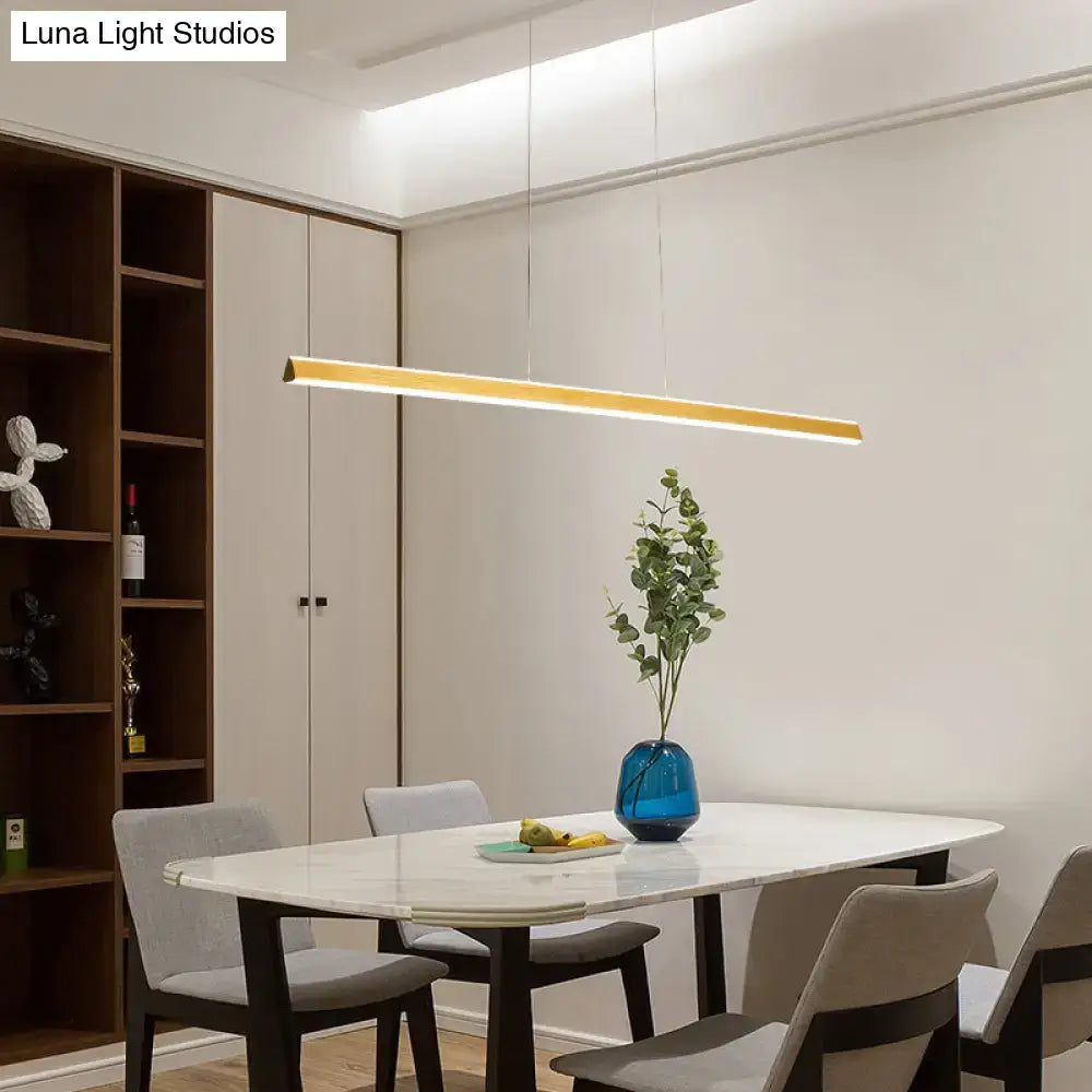 Gold-finished aluminum triangular prism pendant lamp with sleek modern design hanging above dining room table