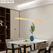 Gold-finished aluminum triangular prism pendant lamp with sleek modern design hanging above dining room table