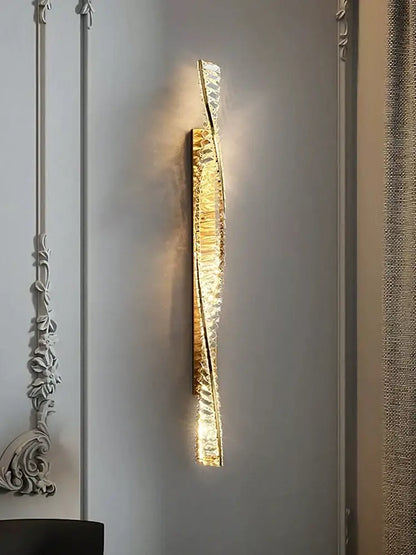 Modern gold twisted crystal wall sconce with decorbites crystal wall accents emitting warm bedroom light