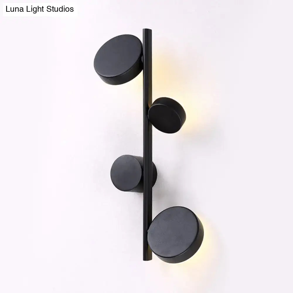 Black minimalist vertical linear sconce light with gold finish and four circular fixtures for modern living room decor