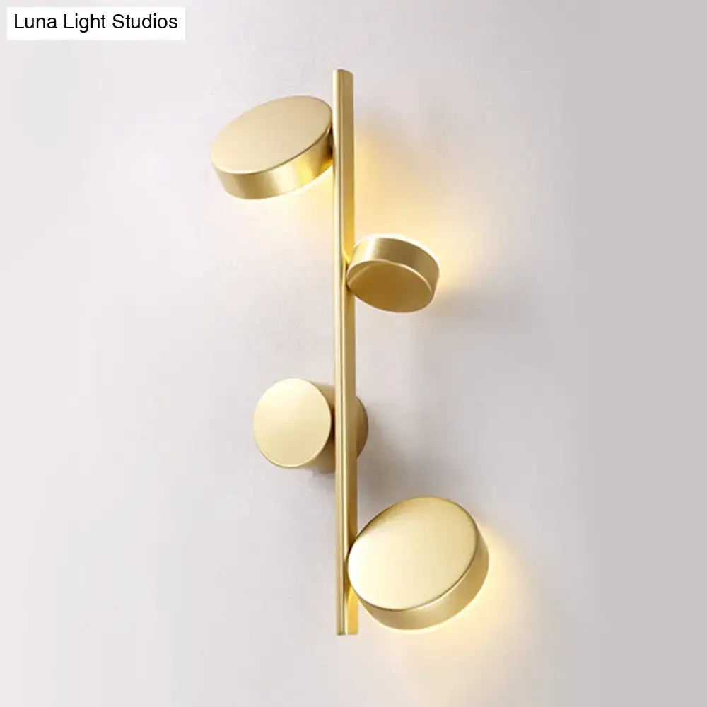 Modern gold vertical linear sconce light with four brushed metal discs in black gold finish for living room use