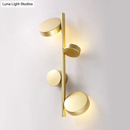 Modern gold vertical linear sconce light with four brushed metal discs in black gold finish for living room use