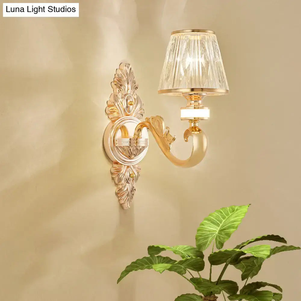 Gold wall lamp fixture featuring an ornate design with a faceted crystal cone shade for modern bedroom use