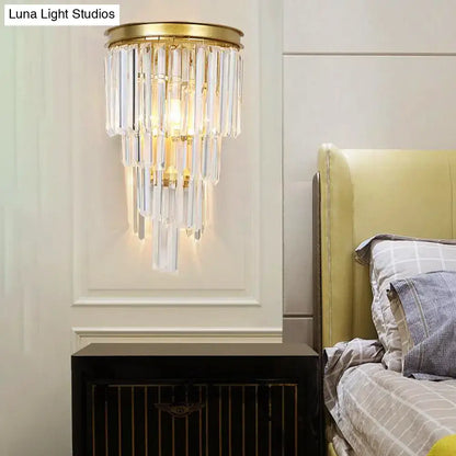 Modern gold wall lamp featuring a gold-toned sconce with cascading clear crystal block prisms for bedroom use
