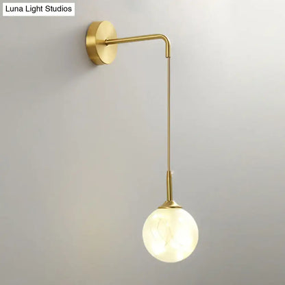 Modern gold wall lamp with slender curved arm and frosted glass shade as bedroom wall sconce light type