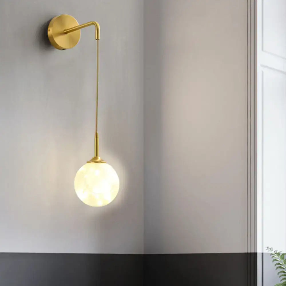 Modern gold wall lamp with slender curved arm and frosted glass shade designed as a bedroom wall sconce light type