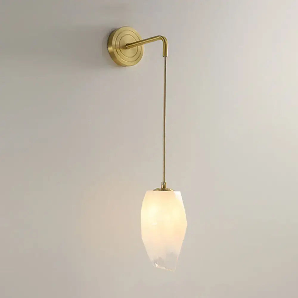 Modern gold wall lamp with a sleek brass arm and opalescent faceted glass shade bedroom light type sconce
