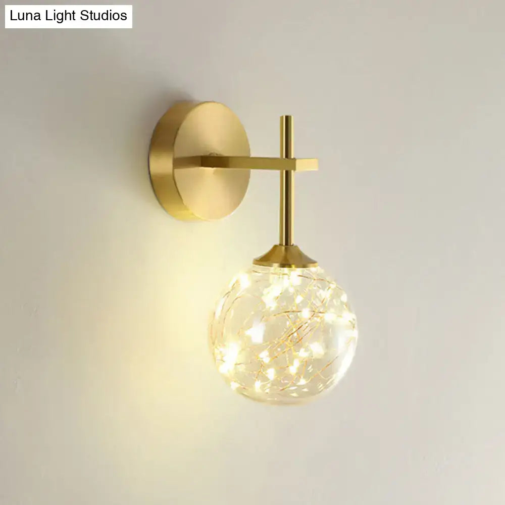 Modern gold wall lamp featuring a spherical glass shade with delicate fairy lights for bedroom lighting type