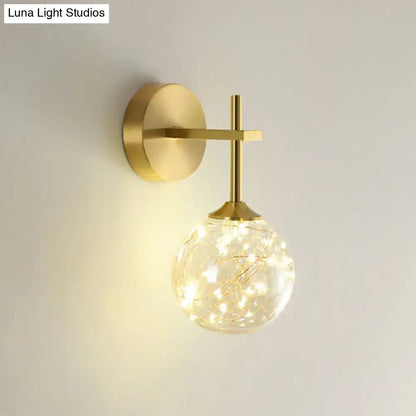 Modern gold wall lamp featuring a spherical glass shade with delicate fairy lights for bedroom lighting type