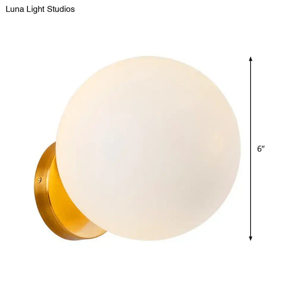Modern gold wall lamp with opal glass shade featuring a 6-inch frosted glass globe and polished brass backplate