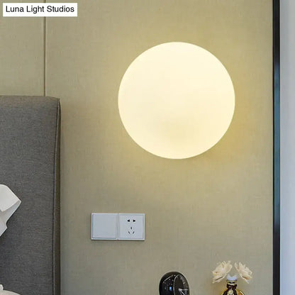 A modern gold wall lamp with opal glass shade features a sleek round design and soft diffused glow for bedrooms