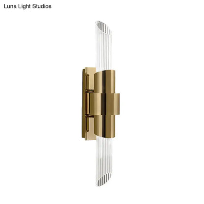 Modern gold wall lamp with sleek metal frame and clear vertically ribbed prismatic crystal shade for bedroom lighting