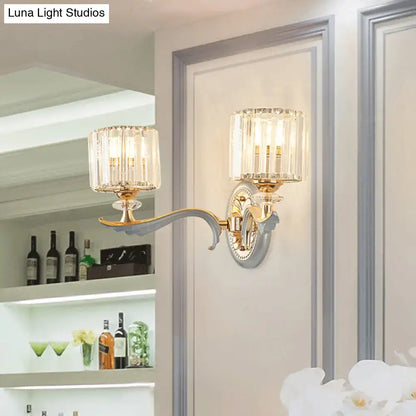 Modern gold wall light with clear crystal shade and two crystal-encased fixtures on a curved ornate arm for living room use