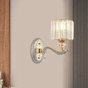 Elegant modern gold wall light with clear crystal shade featuring vertical prisms and decorative backplate for living room