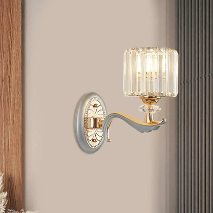 Elegant modern gold wall light with clear crystal shade featuring vertical prisms and decorative backplate for living room