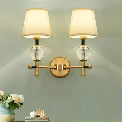 Modern gold wall light with fabric shade and crystal clear glass globes for bedroom lighting