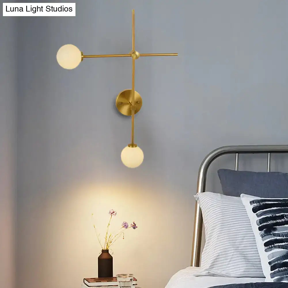 Modern gold wall mount lamp with closed glass and three spherical shades in a crossed wall mount design for living room