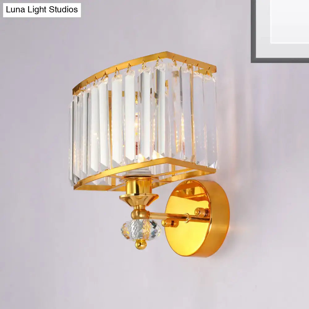 Modern gold wall sconce with clear crystal block rectangular cage and dangling vertical prisms for bedroom lighting