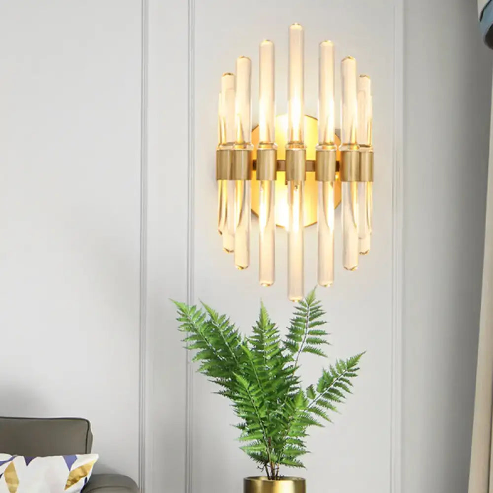 Modern gold wall sconce with clear crystal vertical rods emitting a warm glow for living room lighting