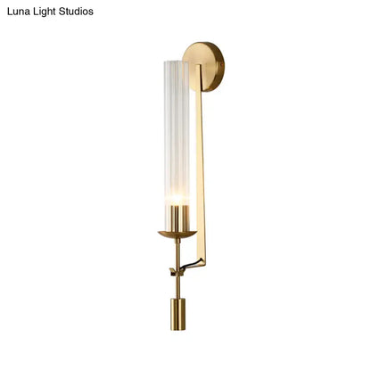 Modern gold wall sconce featuring a clear glass shade with vertical ribs and a sleek metal frame for bathroom lighting