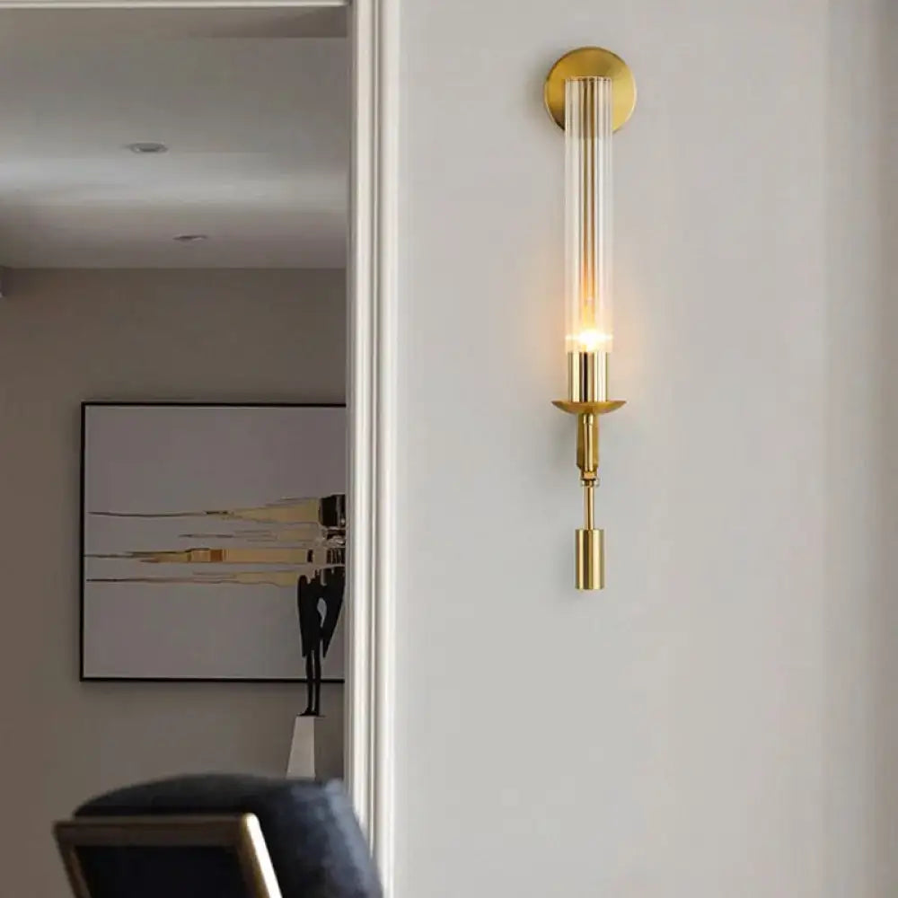 Modern gold wall sconce with clear glass shade featuring a minimalist design ideal for bathroom lighting