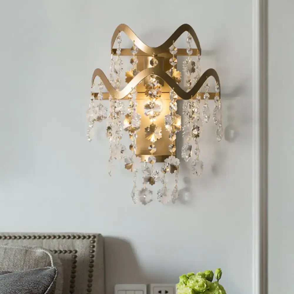 Modern gold wave wired electric wall sconce with intricate wavy metal arms, shell accent, and cascading crystal droplets