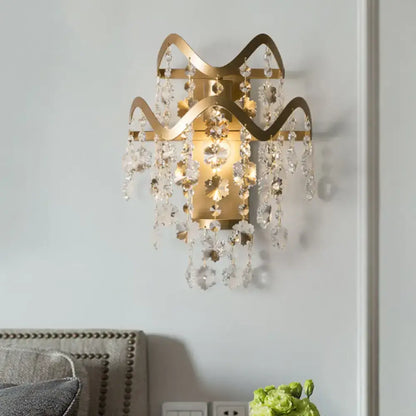 Modern gold wave wired electric wall sconce with intricate wavy metal arms, shell accent, and cascading crystal droplets