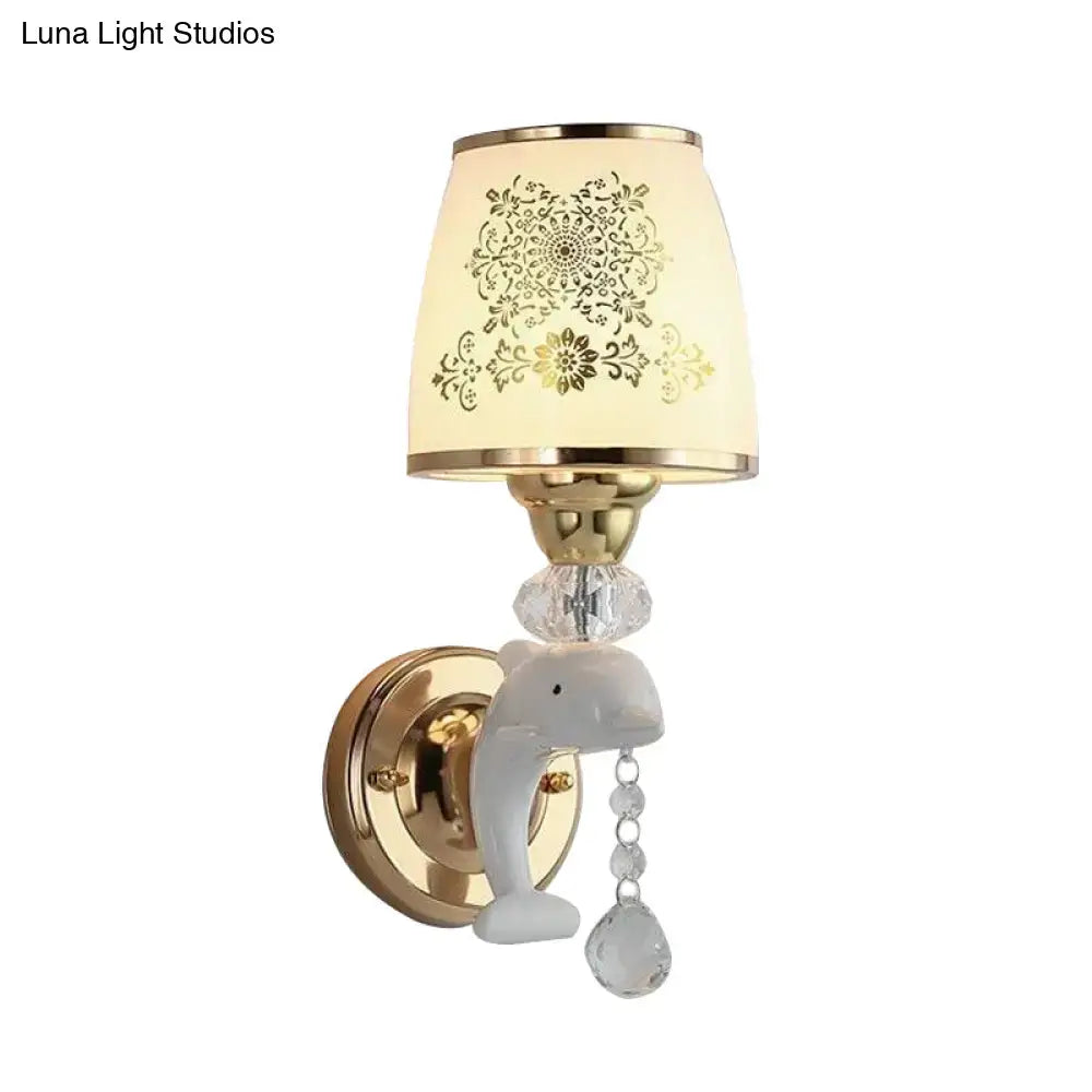 Modern gold and white dolphin wall sconce with ceramic figurine and an off-white opal glass shade featuring golden patterns