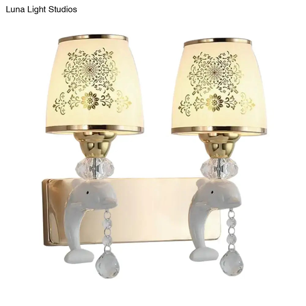 Modern gold and white dolphin wall sconce with ceramic bases, opal glass shade, and gold floral patterned lampshades
