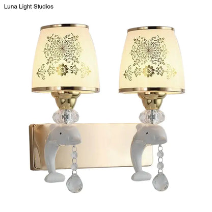 Modern gold and white dolphin wall sconce with ceramic bases, opal glass shade, and gold floral patterned lampshades