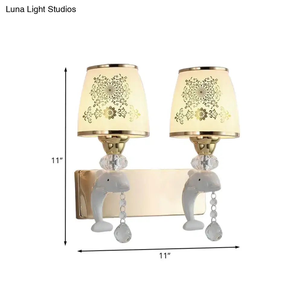 A pair of modern gold and white dolphin wall sconces with opal glass shade and crystal teardrop accents for bedroom use