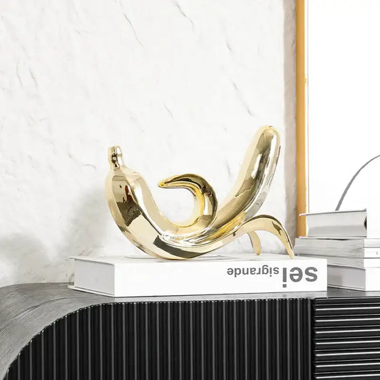Shiny gold ceramic golden banana figurine with smooth reflective surface and elegant curved form for living room decor