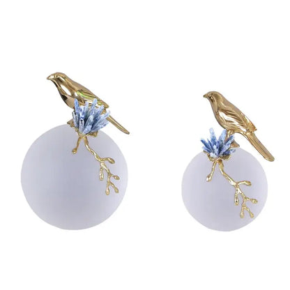 Modern golden bird brass sculpture with delicate gold-toned bird perched on frosted base and blue crystal decorbites golden bird