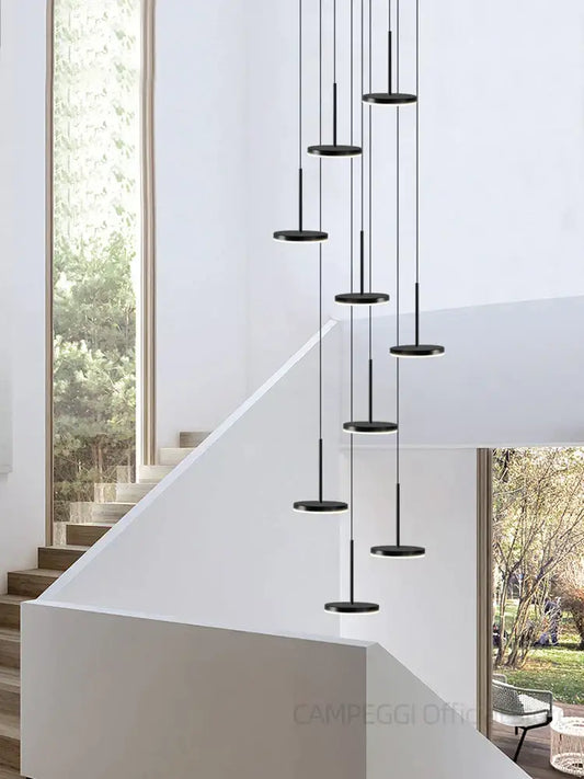 Modern golden black led long black circular pendant chandelier by decorbites hangs above staircase decor