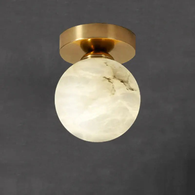 Modern golden brass ceiling lamp featuring a white onyx globe with subtle gray veining by decorbites golden brass