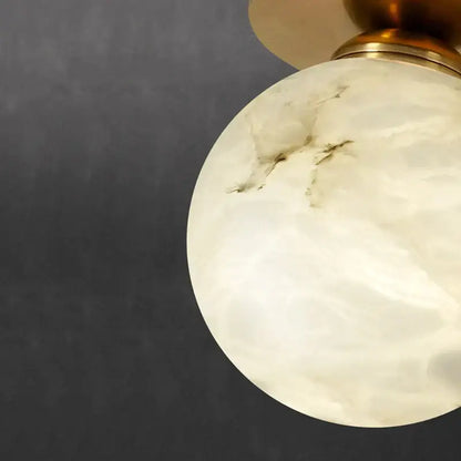 Modern golden brass ceiling lamp with spherical off-white onyx lampshade featuring subtle veining and polished brass fixture
